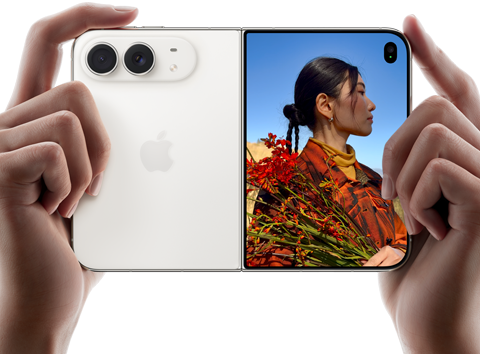 iPhone Duo, color blanco estrella, lo sostienen dos manos en posición horizontal, desplegado, el panel izquierdo muestra el sistema de dos cámaras Fusion traseras de 48 MP, el panel derecho muestra a una persona a quien le toman una foto en la pantalla exterior, la persona fotografiada puede verse en la pantalla con Duo Preview mientras le toman la foto