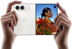 iPhone Duo, color blanco estrella, lo sostienen dos manos en posición horizontal, desplegado, el panel izquierdo muestra el sistema de dos cámaras Fusion traseras de 48 MP, el panel derecho muestra a una persona a quien le toman una foto en la pantalla exterior, la persona fotografiada puede verse en la pantalla con Duo Preview mientras le toman la foto